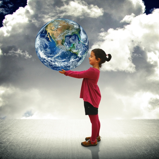 creative photo composite image of child holding the earth in her hands against, a backdrop of grey clouds
